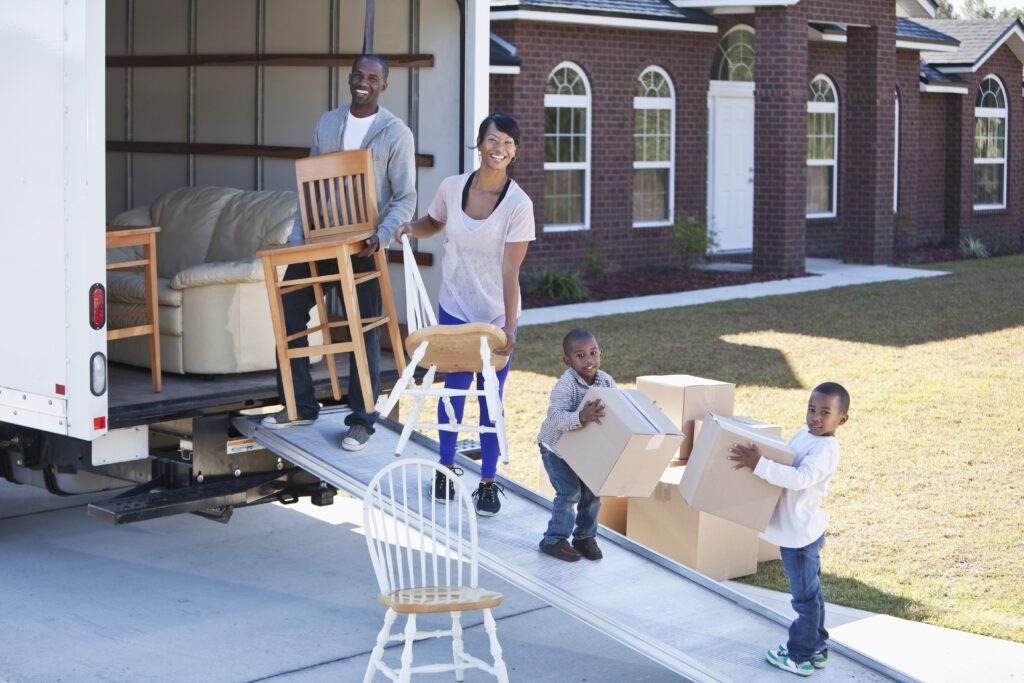 Family unloading a moving truck and moving into a new house. Little boys helping parents unload moving truck.