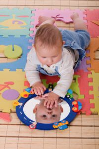 "Beautiful baby touching their reflection in the mirror."