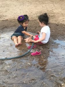two-year-old girls playing in the mud.