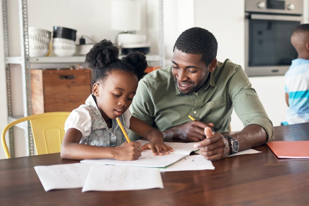 father with daughter helping with homework at home