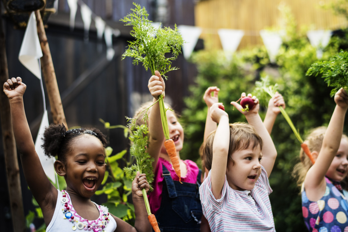 Kids in a vegetable garden with carrot Children Cheering in a Community Garden