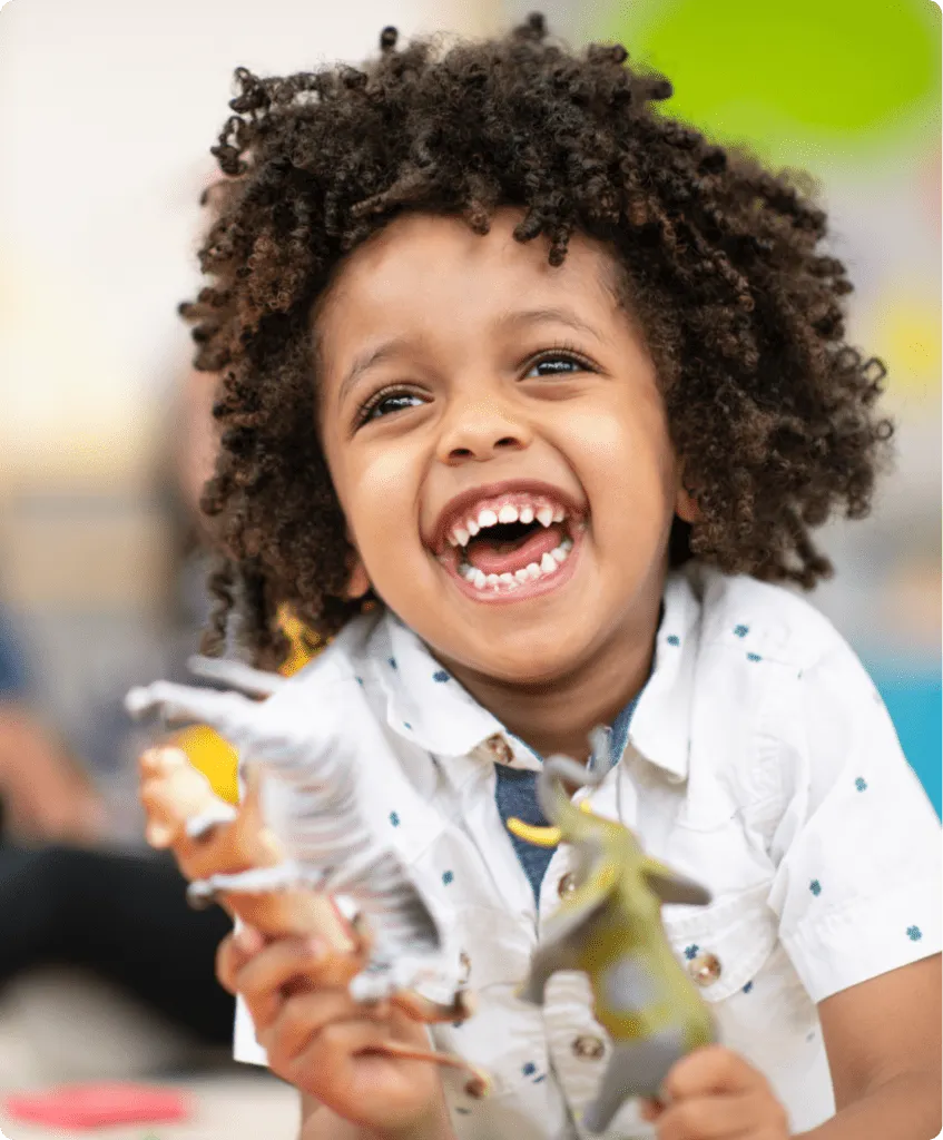 young boy happy smiling playing with animal toys