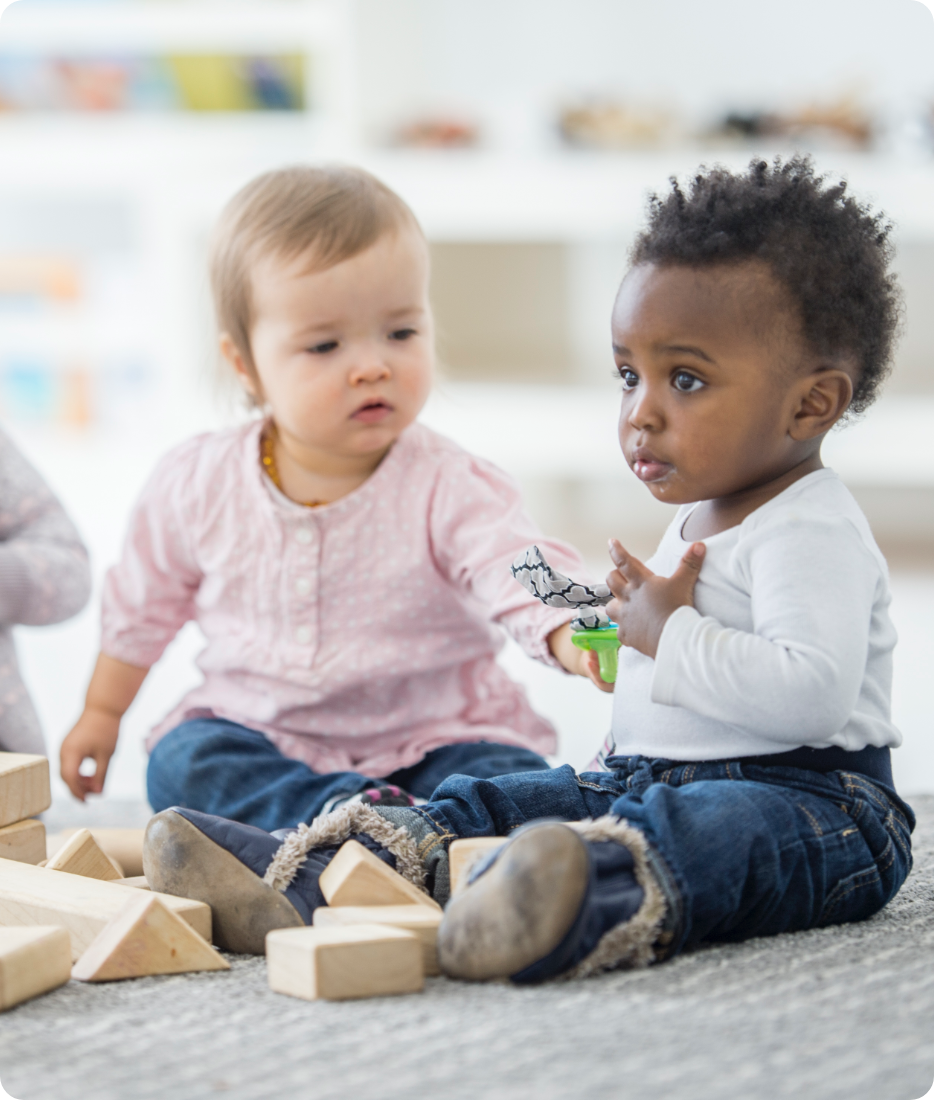 two toddlers engaged in block play