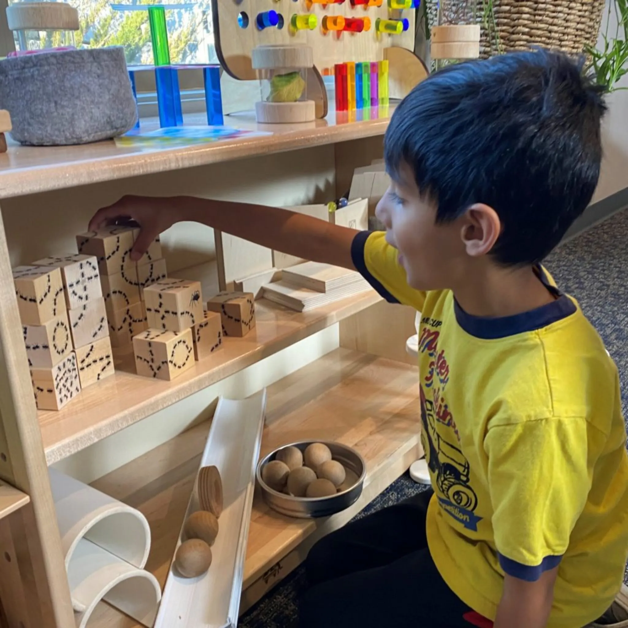 young preschool child classroom picking up wooden blocks