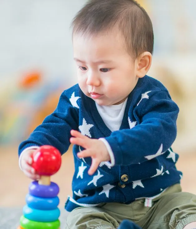 young toddler playing with a rainbow colored ring tower