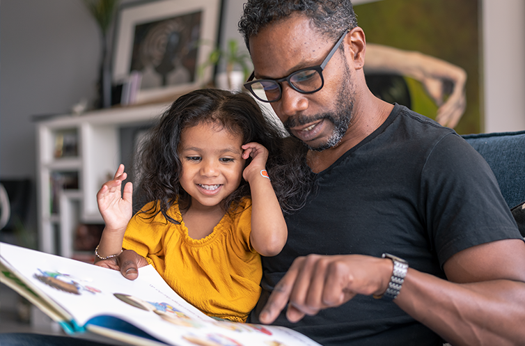 father reading to daughter at home