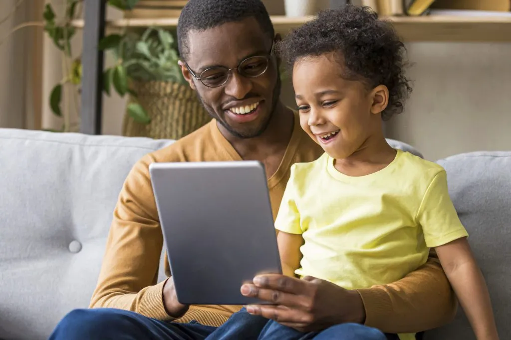 father reading to child via a tablet at home