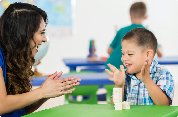 child with special needs playing with blocks while teacher happily observes