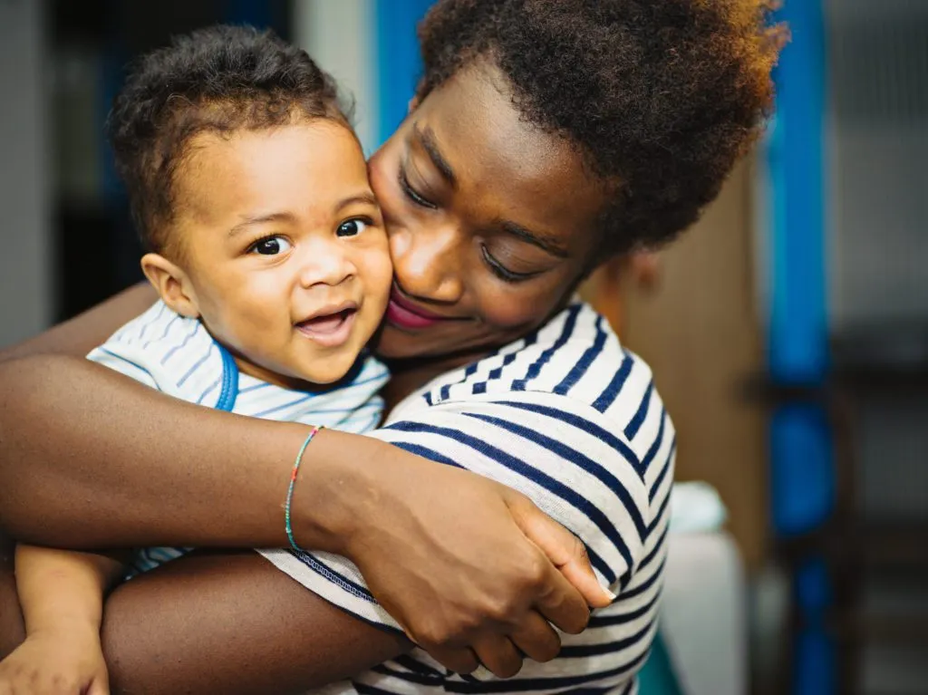 A mother hugs her young son from behind