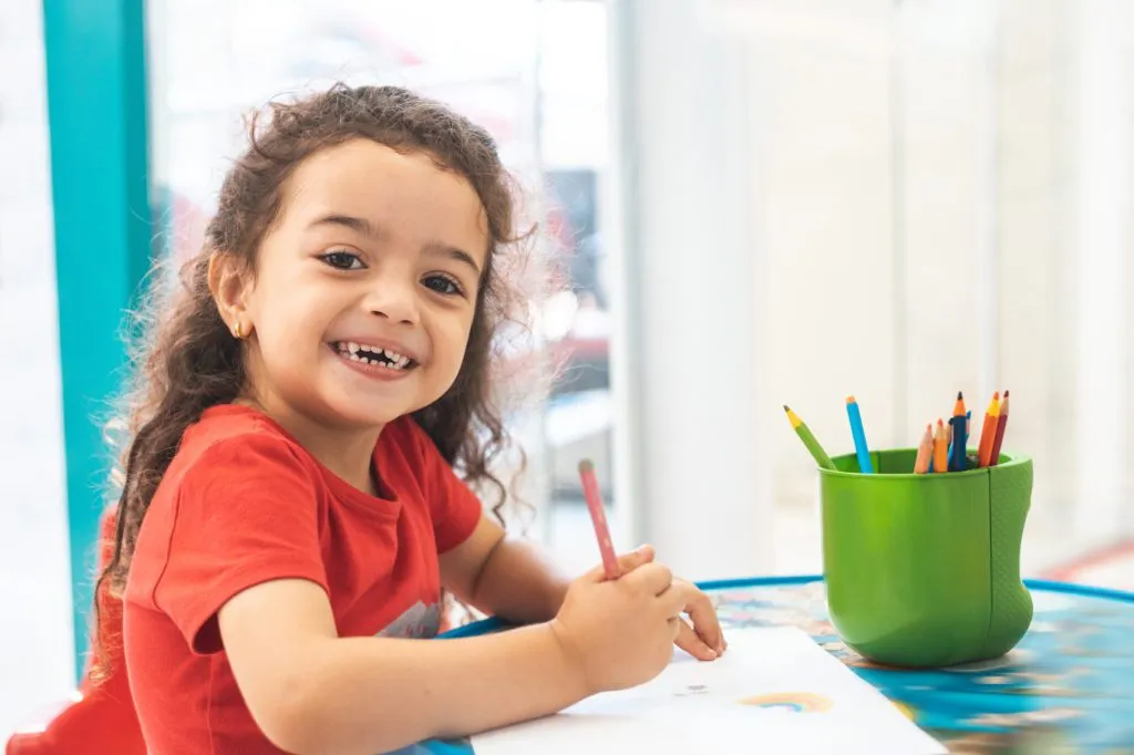 Little girl drawing with colorful pencils