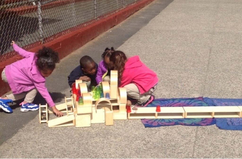 Children count and organize wooden blocks outside