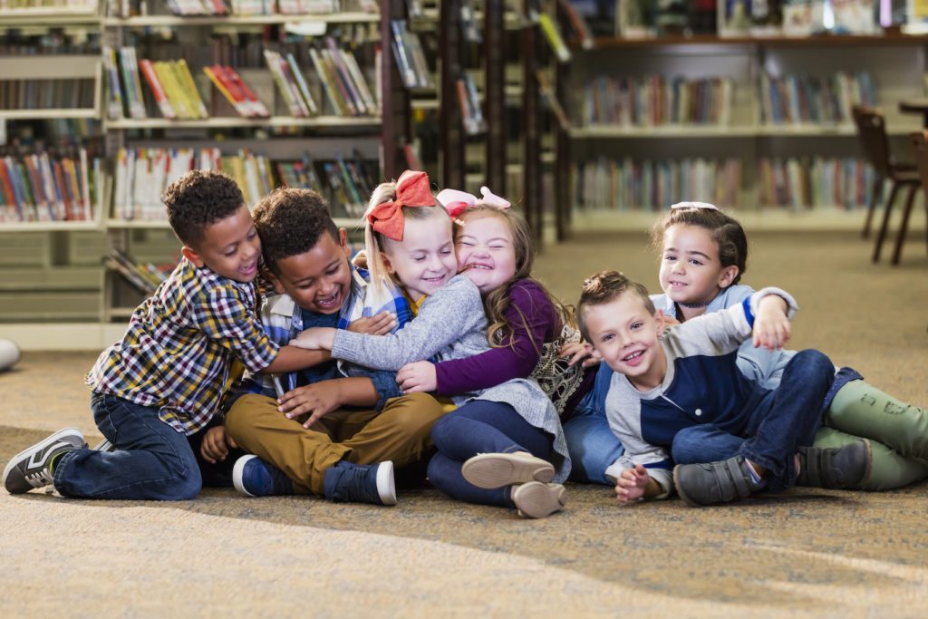 Children in library group hug
