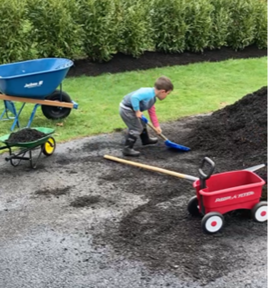 My son, Michael, spreads mulch using a combination of real gardening tools and children’s tools. 