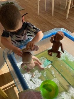 A preschool boy cares for his babies by giving them a warm bath. “The Daddy washes his baby for bedtime.”