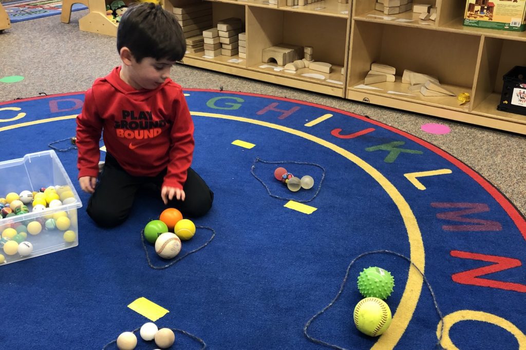 young preschool child sorting various types of balls