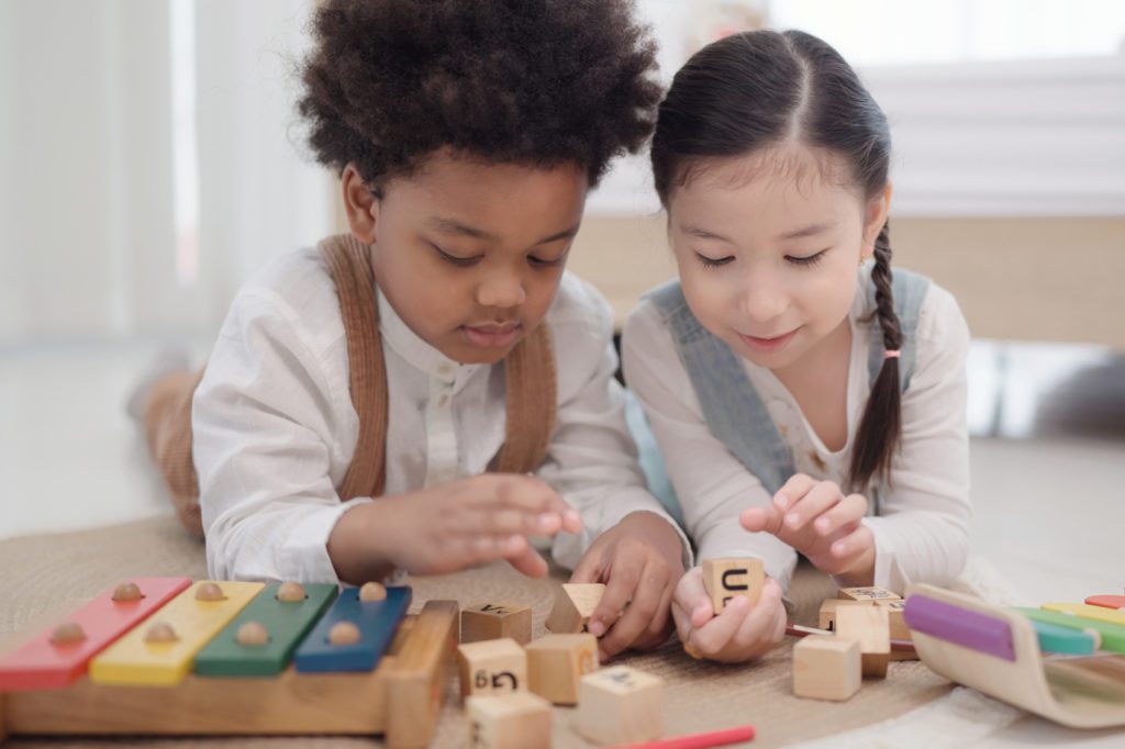 preschool boy and girl playing with blocks and xylophone together