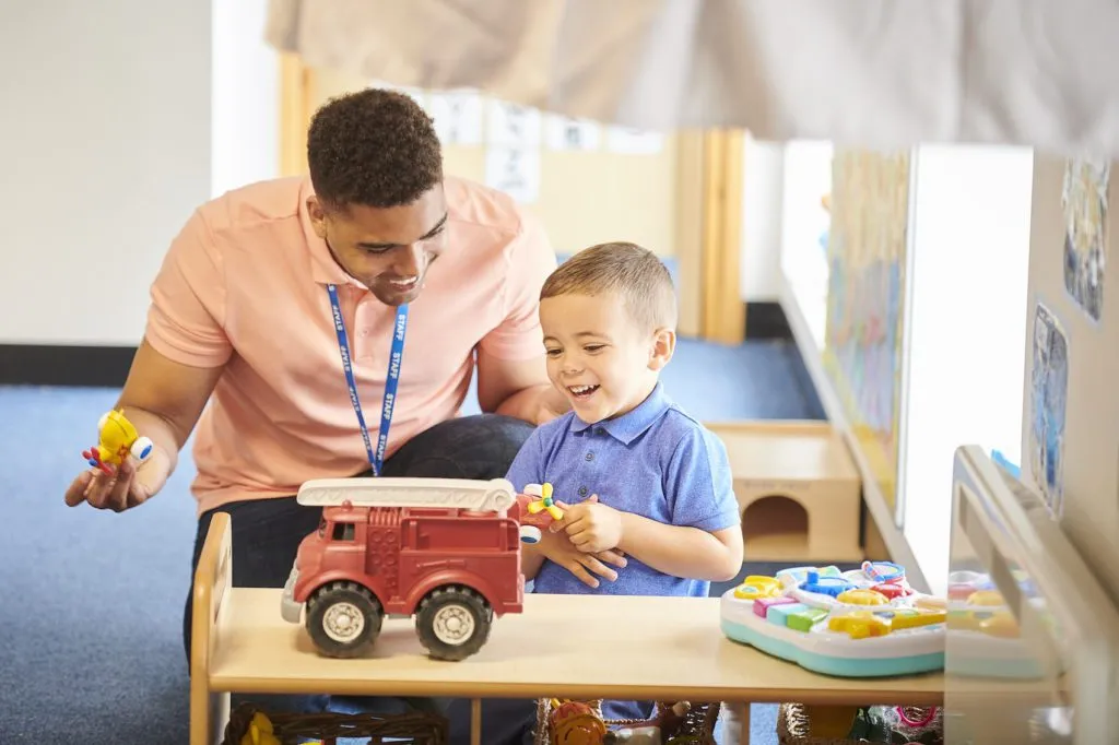 teacher with child engaged in play in a classroom