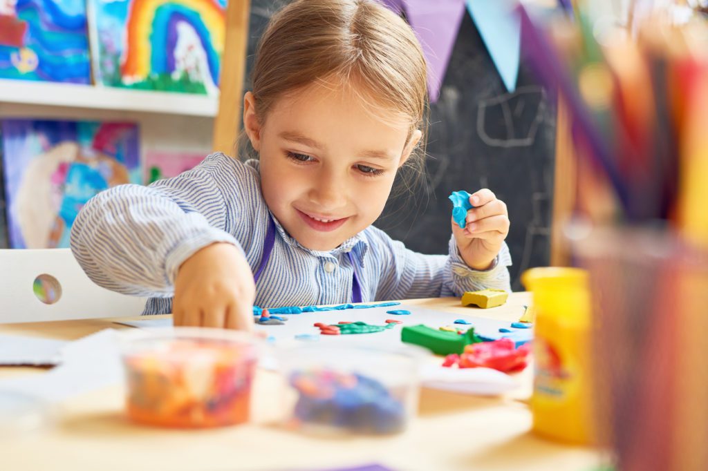 smiling preschool child working with plasticine in art and craft class