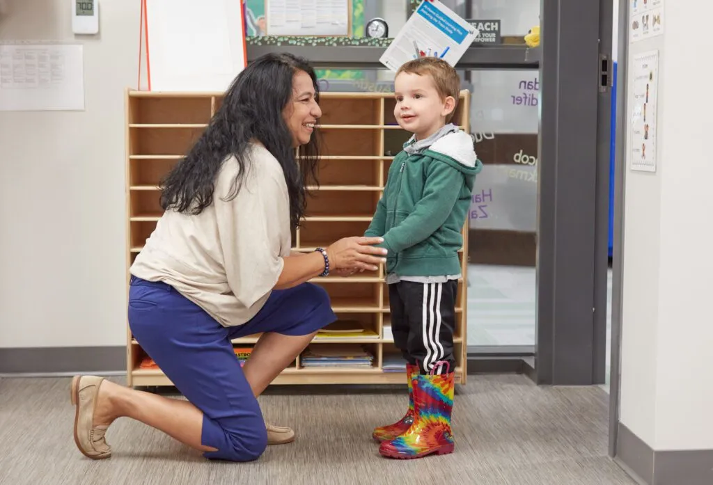 Teacher kneeling down talking to her student