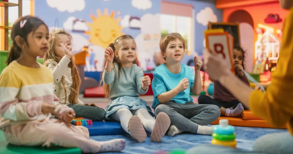 Children looking at teacher who is holding up letter cards