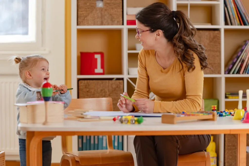 Teacher sitting at the table with a young student